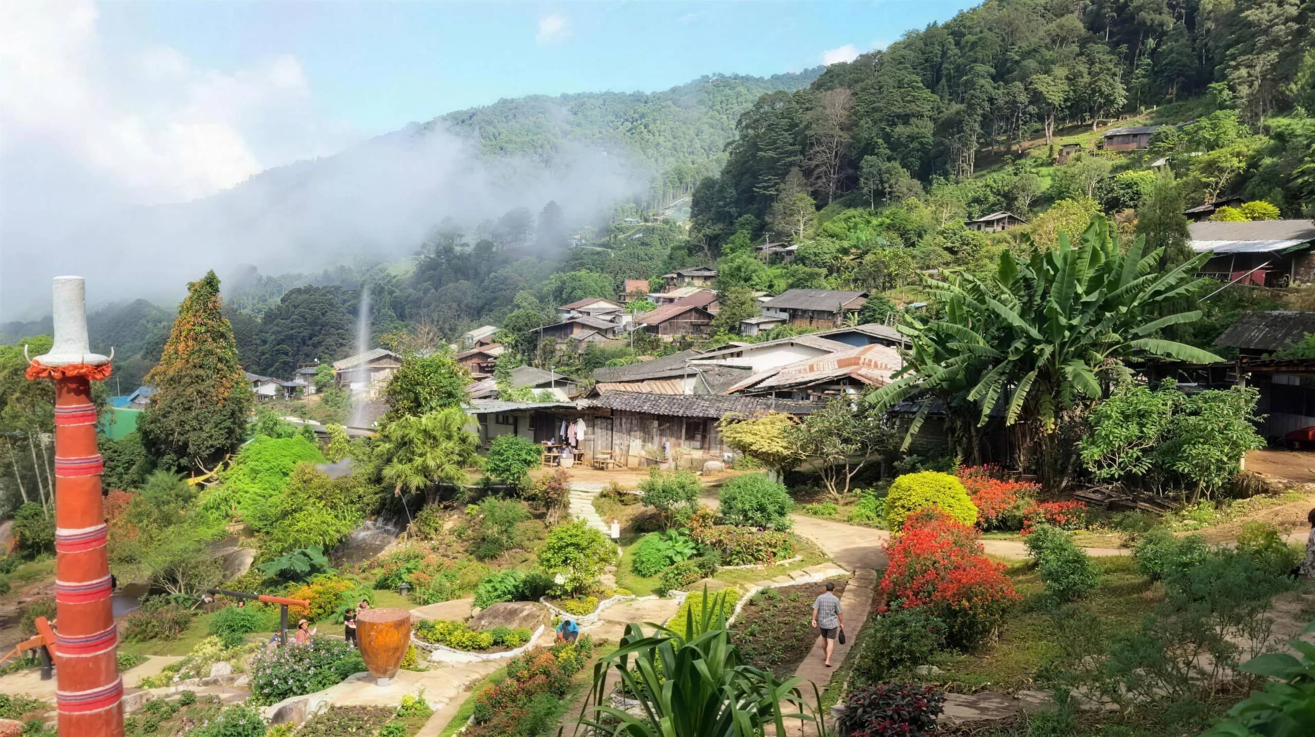 Houses of the Doi Pui Hmong village spread down a forested hillside with mist over the mountains.