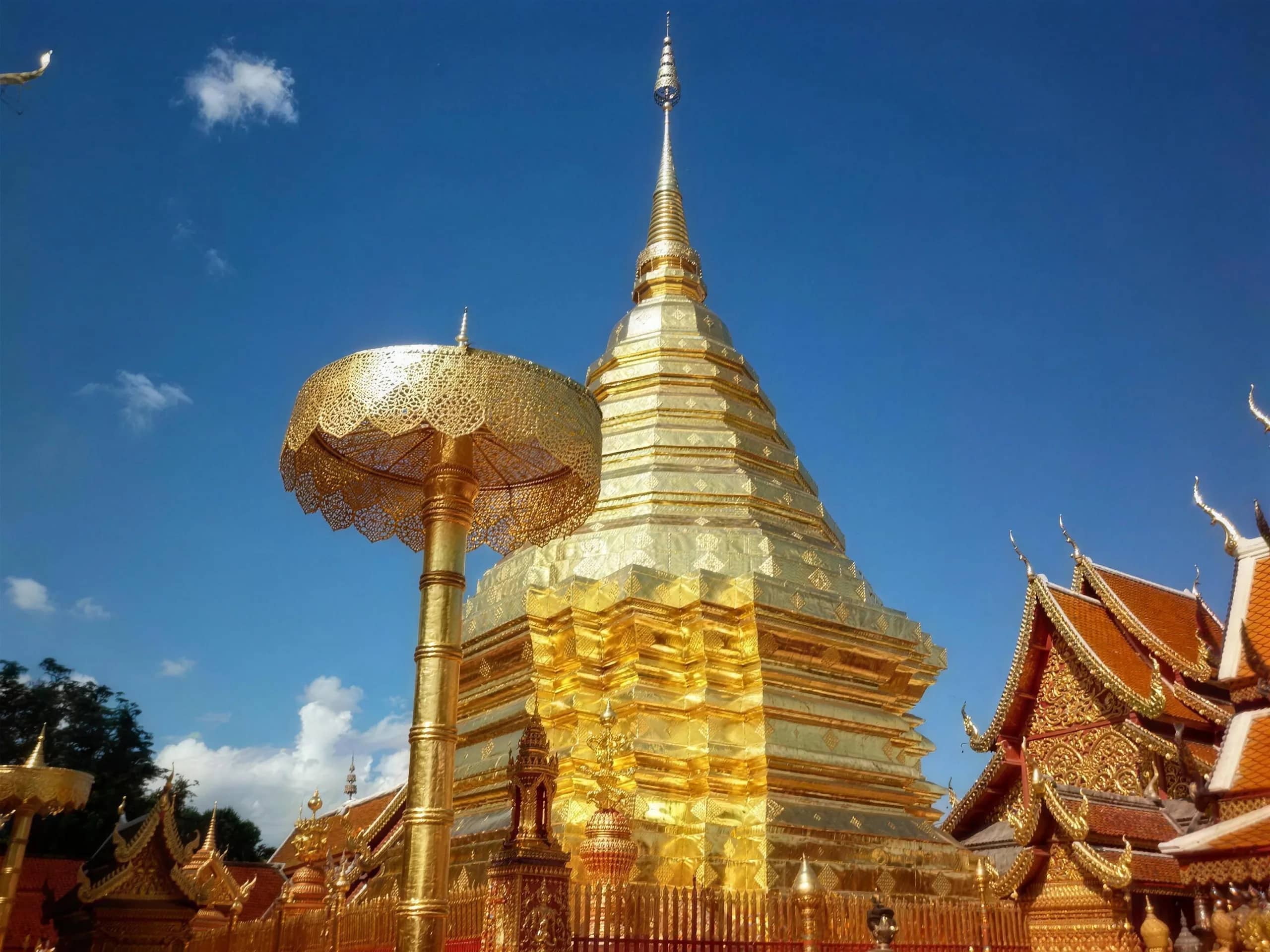 A gilded ceremonial umbrella stands in front of the gold-plated chedi at Wat Phra That Doi Suthep.